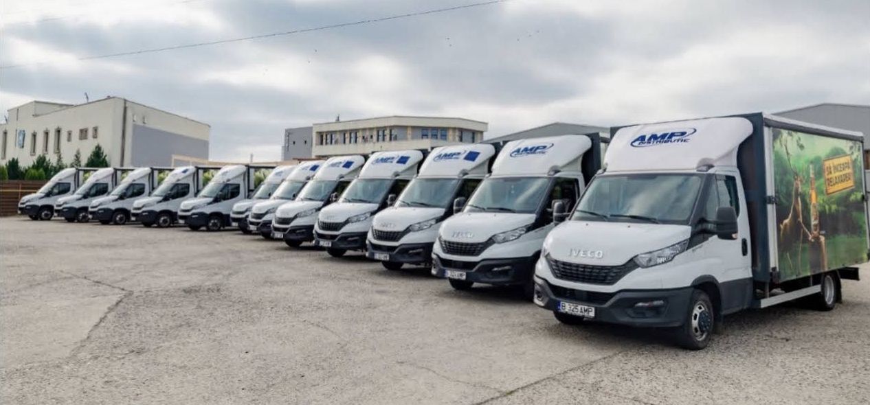 Flota de autoutilitare de distribuție ANA MARIA POP, aliniată în curte.